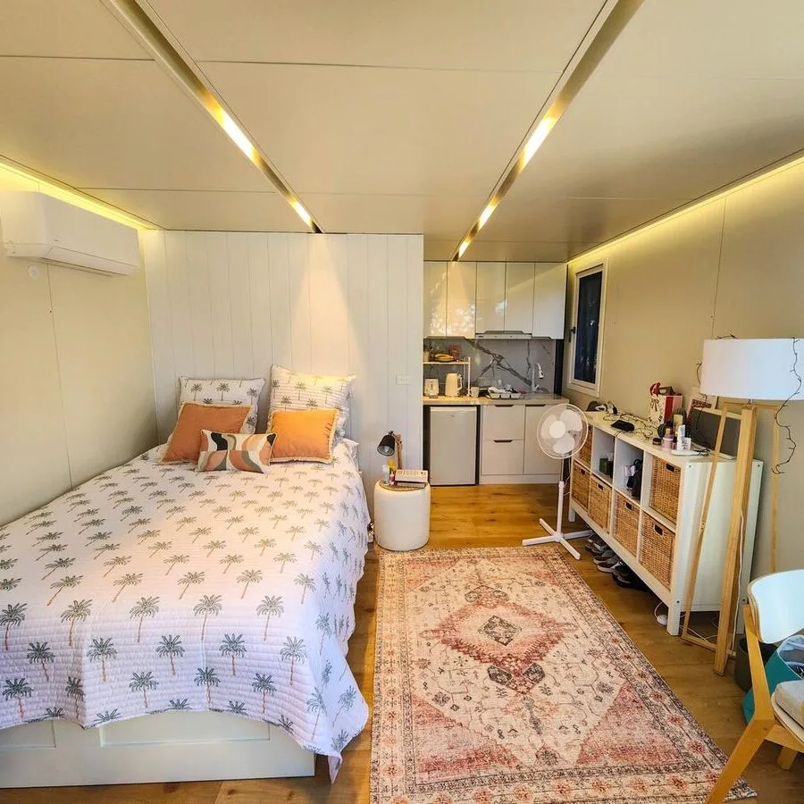 Narraweena_Cabin Cozy prefab cabin interior with bed, kitchenette, and modern lighting in Narraweena